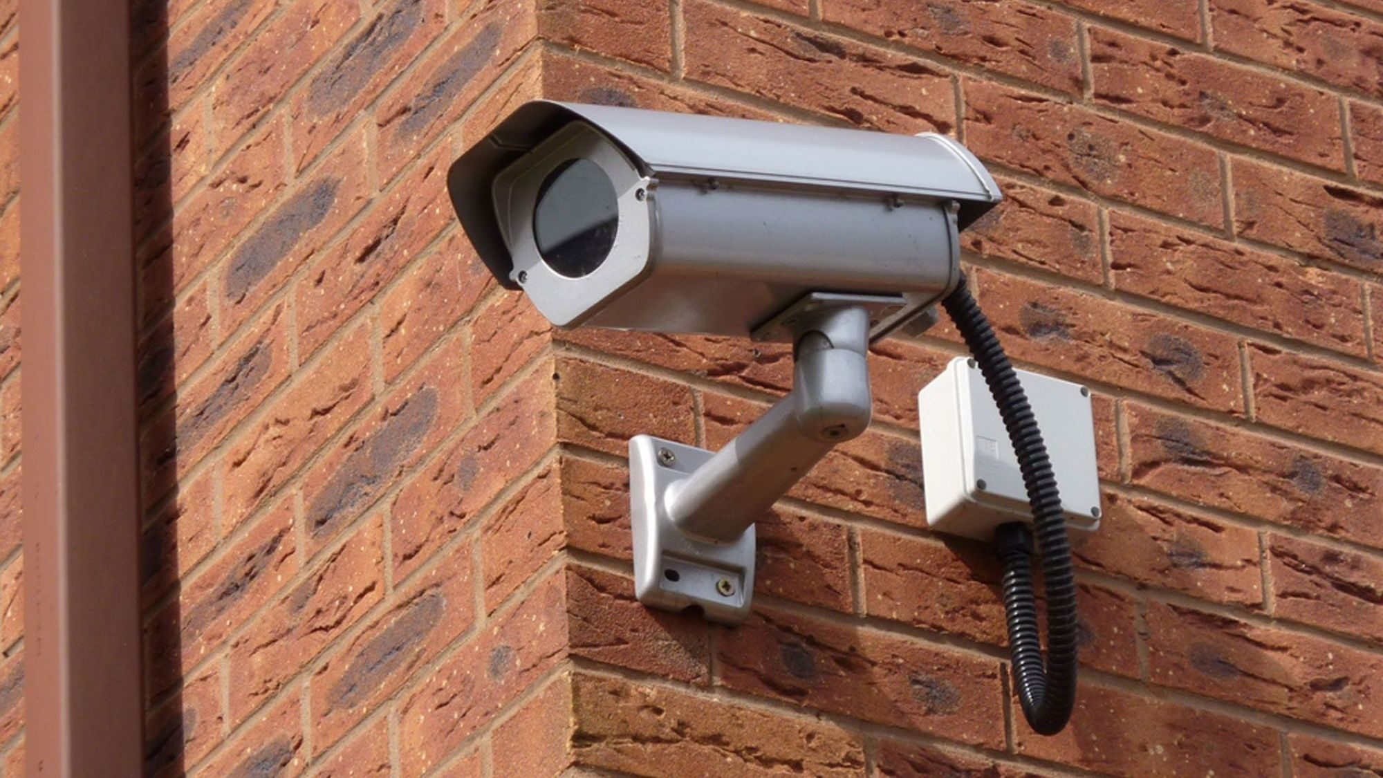 A CCTV camera fixed on a red bricks wall