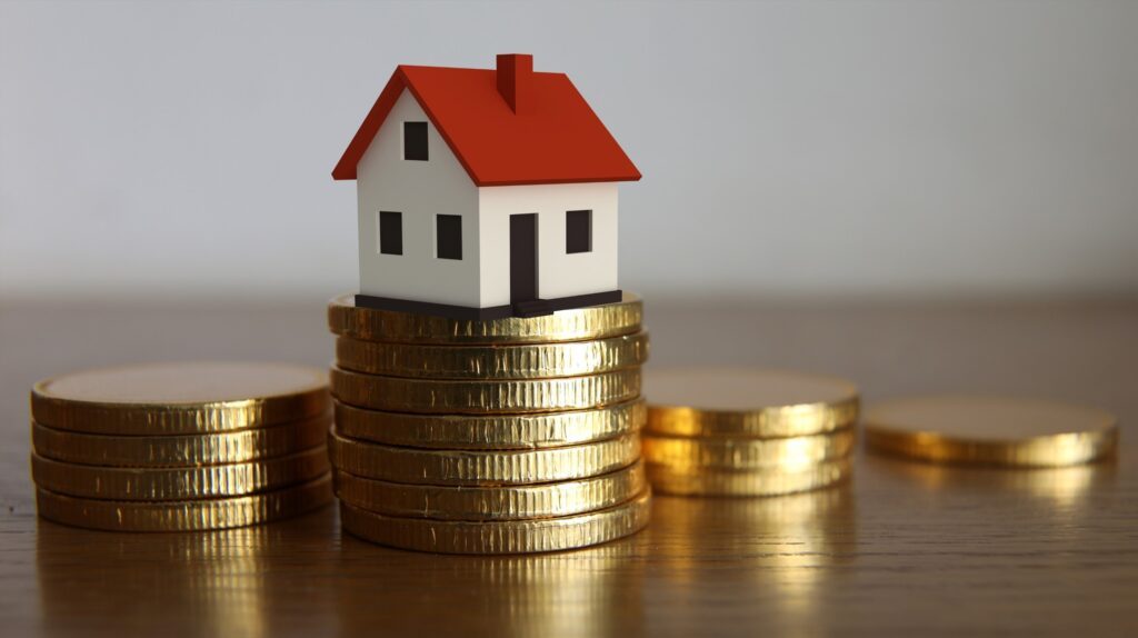 A toy house and some coins showcasing real estate agents