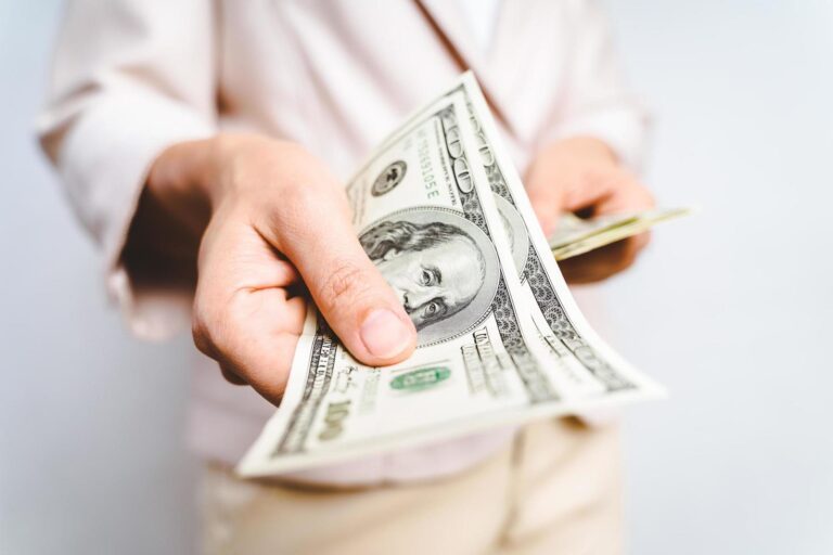 closeup-of-business-woman-hands-proposing-money-us-dollar-bills-on-white-background-money-concept-free-photo